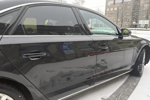 Melns auto sniegotā pilsētas ielā.