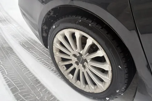 Tum&scaron;a automa&scaron;īna ar tīru, sudrabotu riteņa disku sniegā.