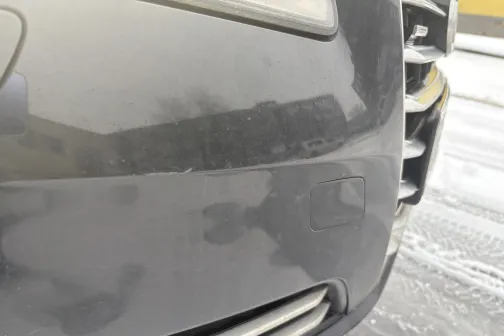 Auto priek&scaron;ējais bamperis ar netīrumiem uz sniega klāta ceļa.