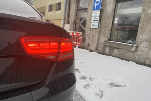 Melna automa&scaron;īna ar ieslēgtām aizmugurējām gaismām sniegotā stāvvietā.