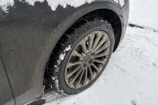 Netīrs auto ritenis sniegā.