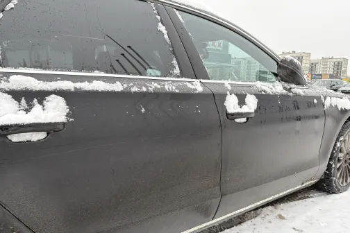 Melnas automa&scaron;īnas sāns ar sniega slāni.