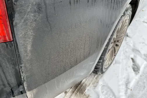 Netīrs automa&scaron;īnas aizmugures spārns uz sniegota ceļa.