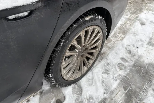 Melna automa&scaron;īna sniegā, redzams aizmugurējais ritenis.