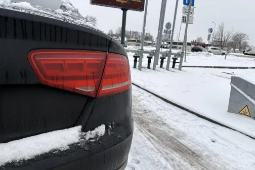 Melnas automa&scaron;īnas aizmugure sniegotā stāvvietā.