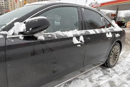 Melns auto sniegā pie degvielas uzpildes stacijas.