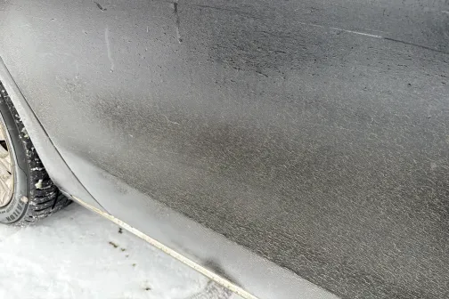 Netīrs automa&scaron;īnas sāns ar redzamu putekļu un dubļu kārtu.