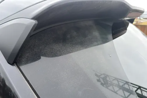 Tum&scaron;a automa&scaron;īna ar putekļainu aizmugurējo logu un spoileru.