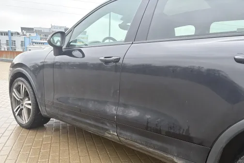 Netīrs tum&scaron;s auto uz bruģēta laukuma fona.