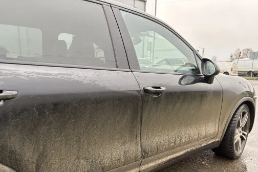 Netīra automa&scaron;īna ar dubļiem uz sānu durvīm uz ielas.