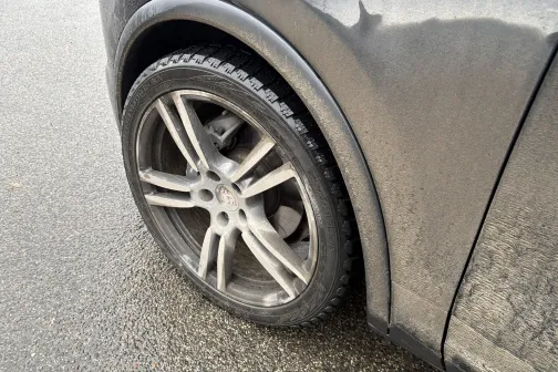 Netīrs automa&scaron;īnas ritenis uz mitra ceļa.