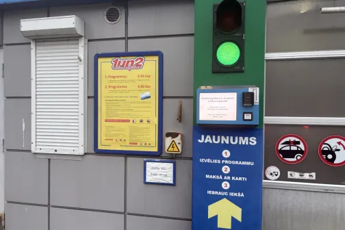 Automa&scaron;īnas mazgātuves ieeja ar zaļu luksoforu un informatīvām zīmēm.