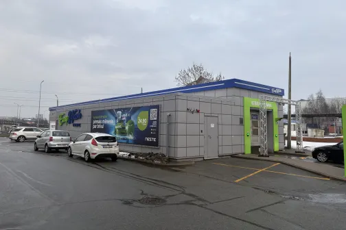 Pa&scaron;apkalpo&scaron;anās automazgātava ar stāvo&scaron;iem auto pie ēkas.