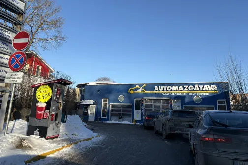 Automa&scaron;īnas rindā pie zilas automazgātavas saulainā dienā.