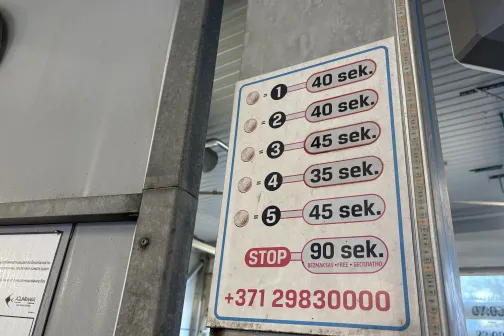 Mazgā&scaron;anas programmu saraksts ar laikiem, piestiprināts pie metāla staba.