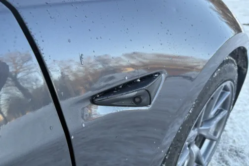 Mitrs auto virsbūves sāns ziemā, redzams aizmugurējo riteņu loks.