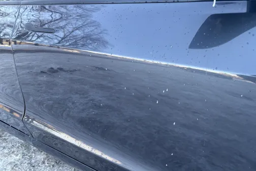 Automa&scaron;īnas virsma ar netīrumu un ūdens pilieniem, blakus sniegs.