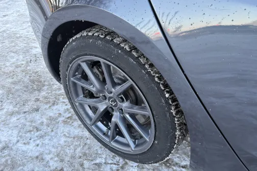 Pelēka automa&scaron;īna ar sniega klātu riepu, ziemas fonā.