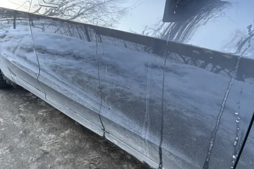 Netīra automa&scaron;īnas sānu daļa ar dubļiem un ūdens pilēm.