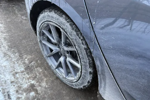 Netīrs pelēks auto ritenis un riteņa arka ziemā.