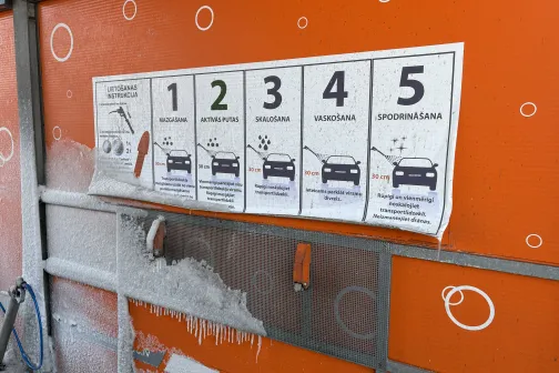 Iesalu&scaron;as auto mazgā&scaron;anas instrukcijas uz oranžas sienas.