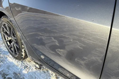 Netīrs automa&scaron;īnas sāns ar redzamiem putekļiem un ziemas ainavu.