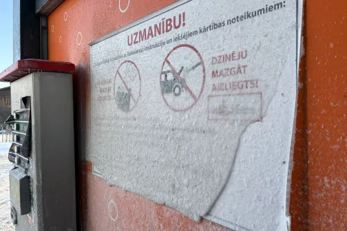 Netīrs zīmes stends pie automazgātuves sienas.