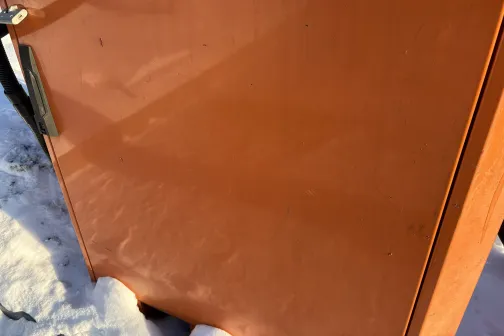 Oranža metāla virsma ar dažiem sniega plankumiem.