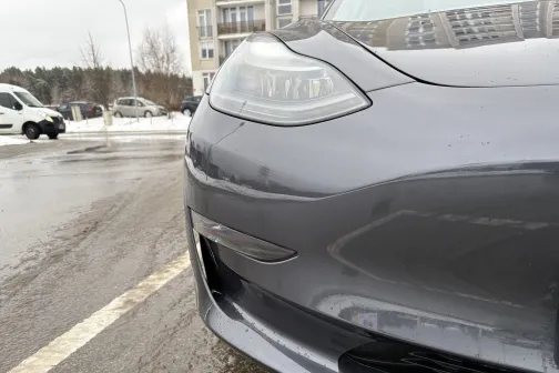 Pelēka automa&scaron;īna stāv stāvvietā lietainā dienā.