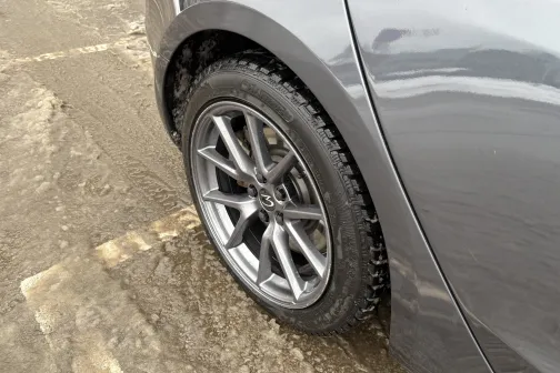 Pelēka automa&scaron;īna uz slapja bruģa, redzams aizmugurējais ritenis.