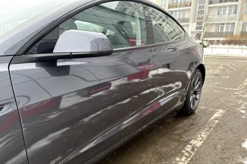 Pelēka automa&scaron;īna ar sniega pārklātiem sāniem stāvvietā.