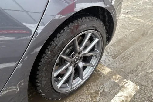 Sudraba auto ritenis ar lieto disku uz netīra ceļa.