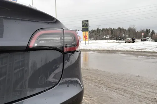 Sudraba auto aizmugure ziemā ar dubļainiem ceļiem un sniegu fonā.