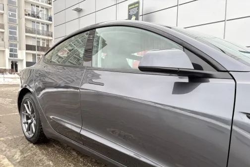 Pelēka automa&scaron;īna blakus mūsdienīgai ēkai.