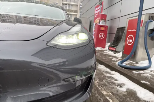 Pelēks auto ar ieslēgtām gaismām pie pa&scaron;apkalpo&scaron;anās automazgātavas ziemā.