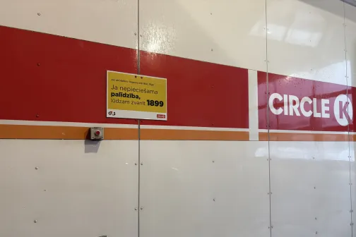 Circle K automazgātuve ar zīmi uz baltas un sarkanas sienas.