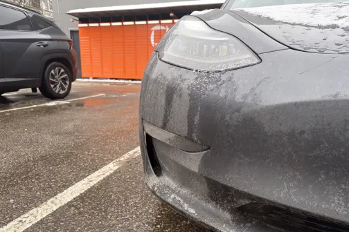 Netīra pelēka automa&scaron;īna stāvvietā blakus ēkai.