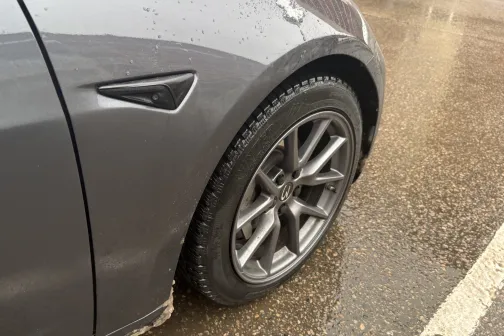 Pelēka automa&scaron;īna ar mitrām riepām un ūdens pilieniem uz virsmas.