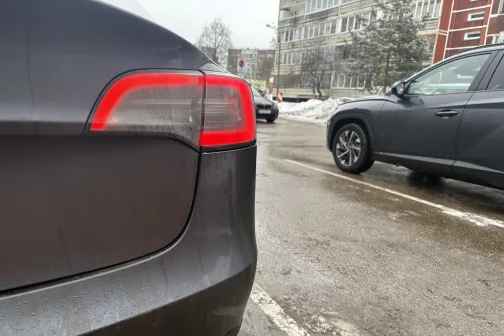 Auto aizmugure ar ieslēgtu aizmugurējo lukturi, stāvlaukums ziemā.