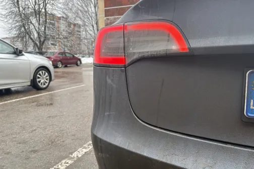 Netīrs auto aizmugures lukturis sniegotā stāvlaukumā.