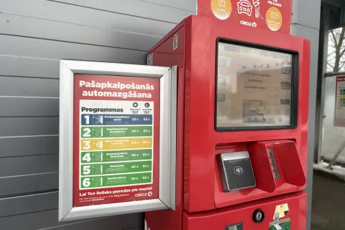 Sarkans pa&scaron;apkalpo&scaron;anās automazgātavas maksājumu automāts ar programmu sarakstu.