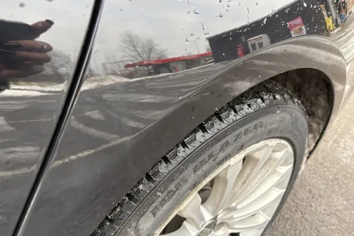 Melns auto ar netīriem riteņiem pie automazgātavas ziemas laikā.