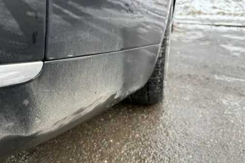 Netīras automa&scaron;īnas sānu skats uz slapjas brauktuves.