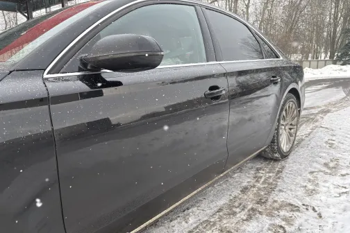 Tum&scaron;i pelēks auto ziemas dienā ar sniegu uz ceļa.