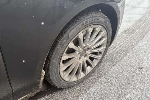 Auto priek&scaron;ējais ritenis uz sniegota ceļa.