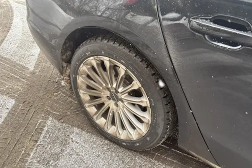 Melnas automa&scaron;īnas aizmugurējais ritenis ar sudraba diskiem.