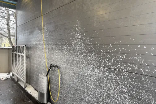 Augstspiediena mazgā&scaron;anas &scaron;ļūtene ar putām pret sienu automazgātavā.