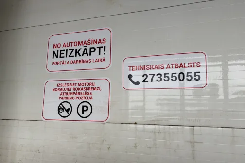 Brīdinājuma zīmes automazgātavā pie sienas.