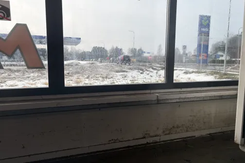 Skats pa logu uz sniegotu ainavu un ceļa zīmēm.