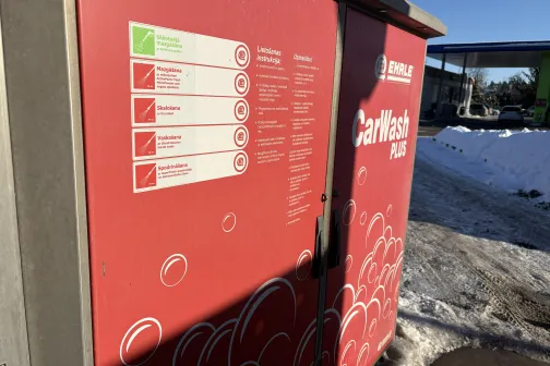 Sarkanā automazgātuves stacija ar instrukcijām uz sāniem, ziemas ainava.